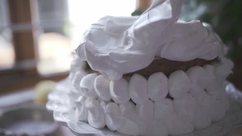 A Person Icing A Baked Cake With White Meringue