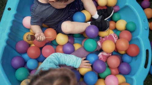 Kids Playing On A Large Plastic Basin Filled With Colorful Balls