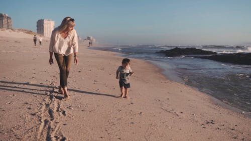 Een Moeder En Een Kind Die In De Strandkust Lopen