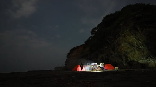 People Camping On The Shoreline Beside A Mountain