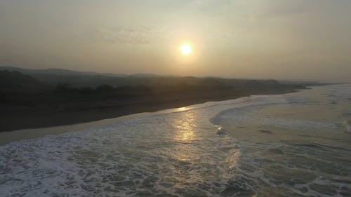 배경에 일몰의 볼 수있는 해안에 돌진 파도