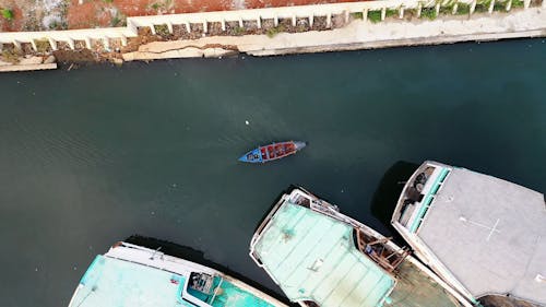 Một Chiếc Thuyền Máy Nhỏ Di Chuyển Qua Những Chiếc Thuyền đánh Cá Lớn Trong Một Cảng Biển