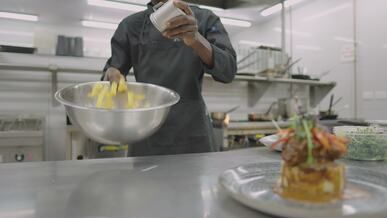 professional chef seasoning dish in modern kitchen