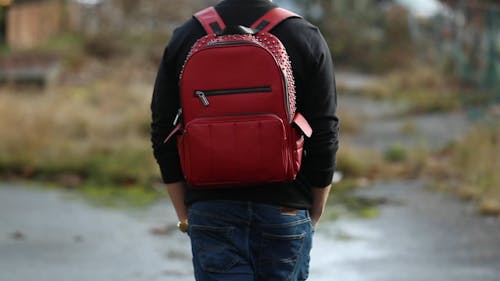 A Person Is Walking With A Red Backpack