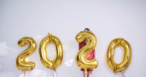 Подбрасывание воздушных шаров с цифрами, указывающее на Новый год в воздухе