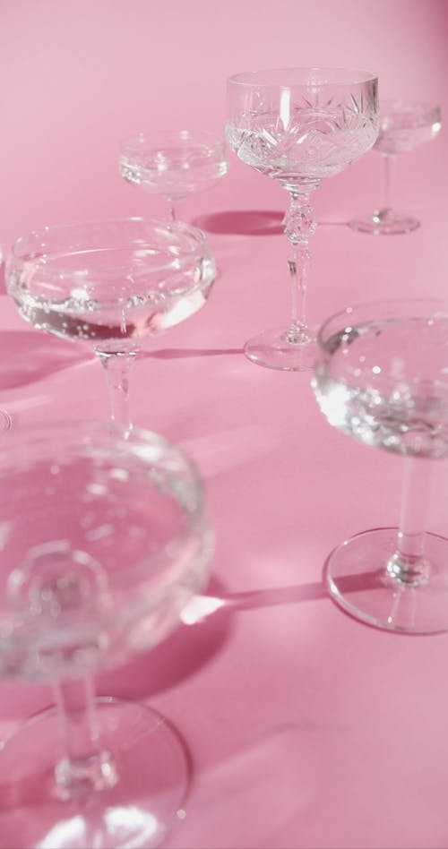 Different Kind Of Crystal Cocktail Glasses Over A Table Covered In Pink Cloth