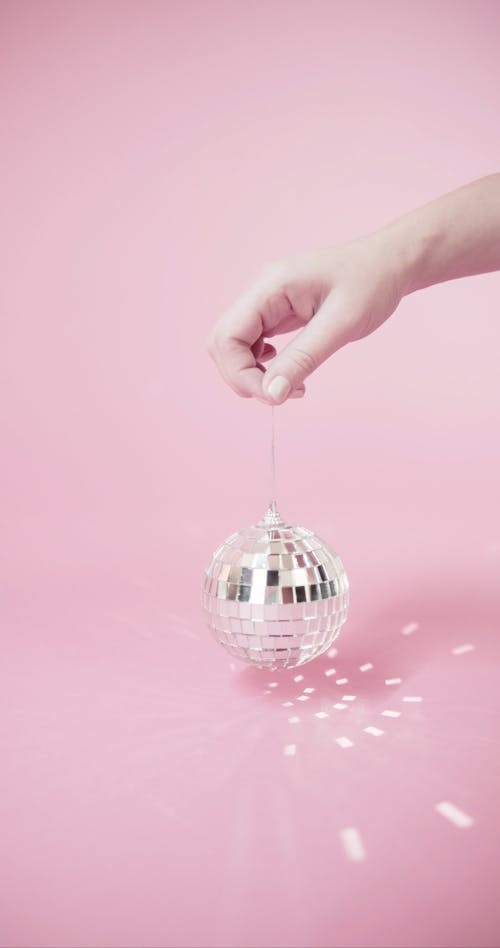 Person Holding A Mirror Ball With Light Reflections On Background
