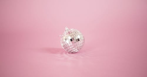 A Small Mirror Ball On Pick Background With Lighting Effects