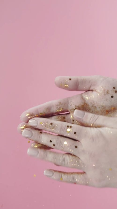A Person Rubbing Off His Hands To Remove Gold Confetti Glitters 