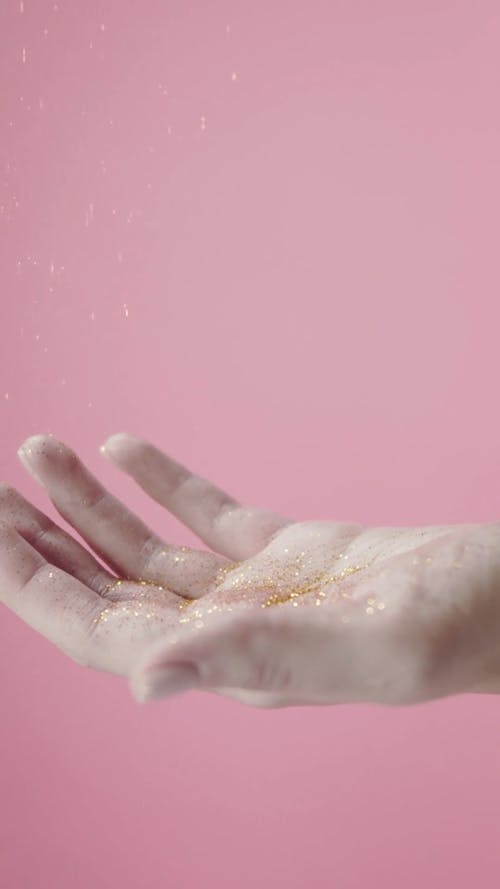 Sprinkling Gold Glitters On A Person Palm