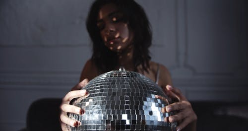 A Woman Holding A Mirror Ball Producing Dots Of Light