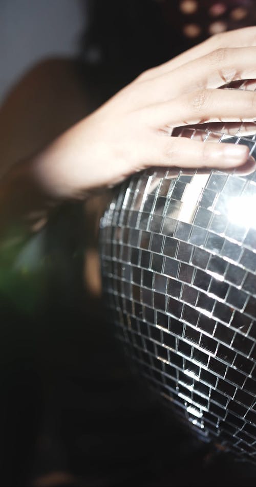 A Woman Holding A Mirror Ball For Light Effects