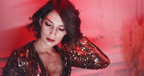 A Woman In A Gold Dress Having A Sip Of Alcoholic Drink While Posing In A photo Shoot