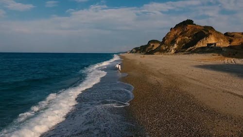 A Couple Holding Hands While Waking In A Beach Shore