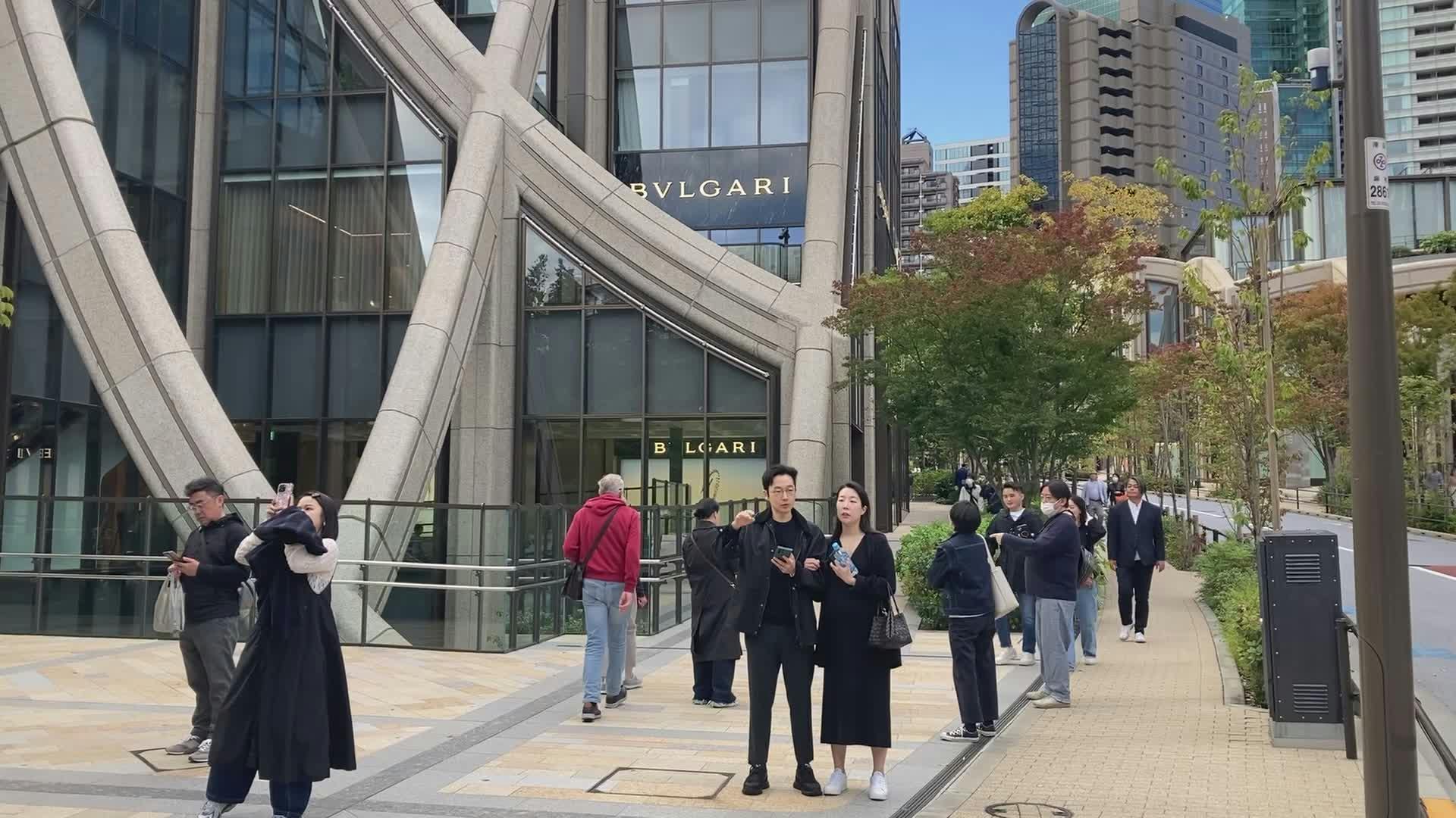 people walking by bulgari store in urban setting 34575153
