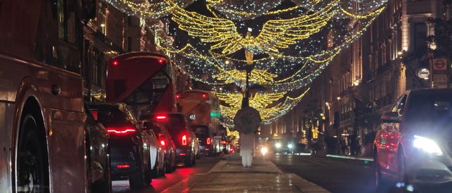 Christmas lights and traffic on a London street at night.