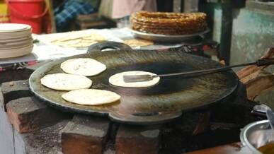 street vendor cooking flatbreads on griddle