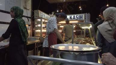 people buying on a market food stall
