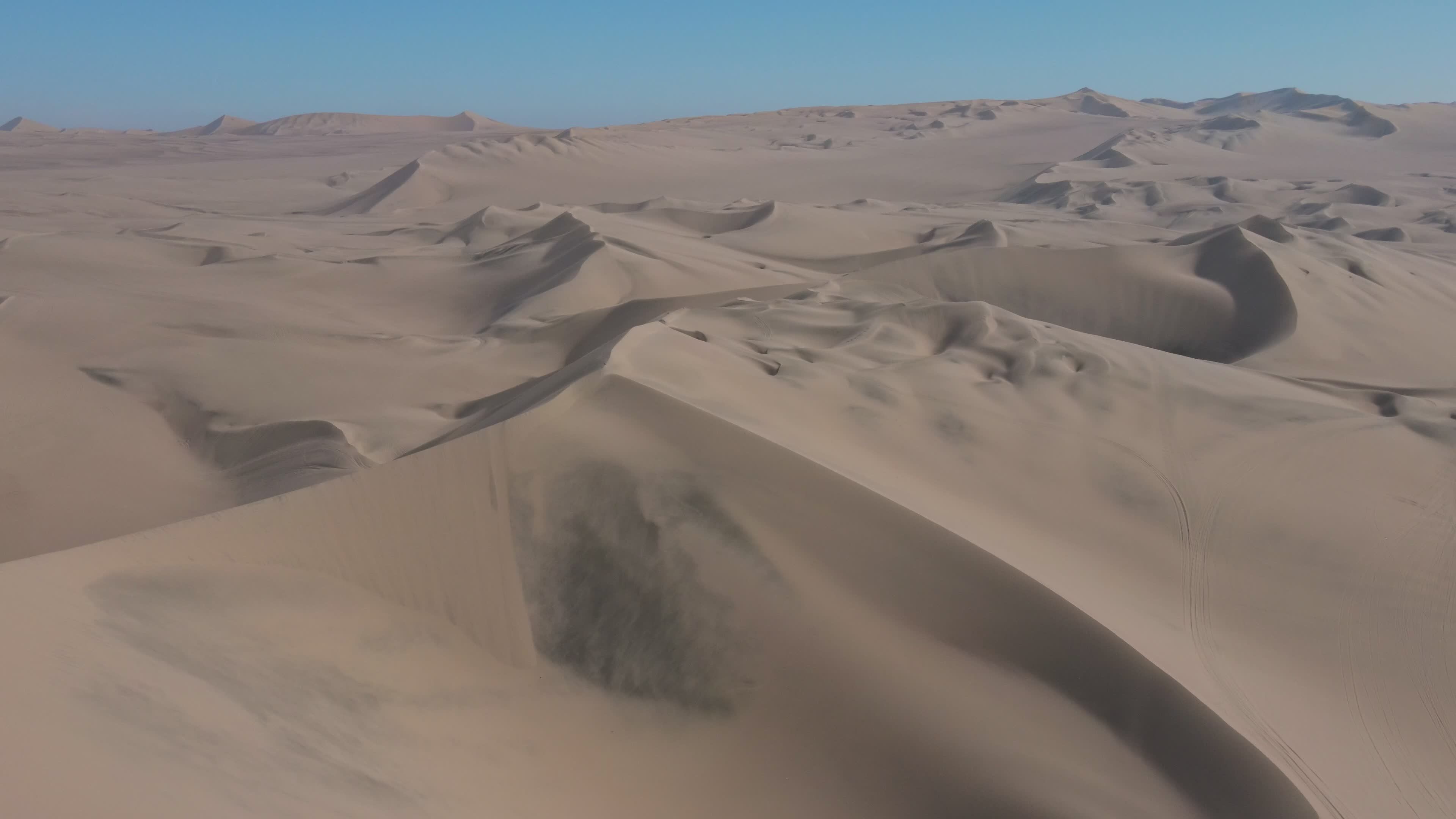 Aerial view over rippled golden sand dunes at first light