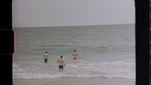 ビーチの海の水に浸る若い男性のグループ