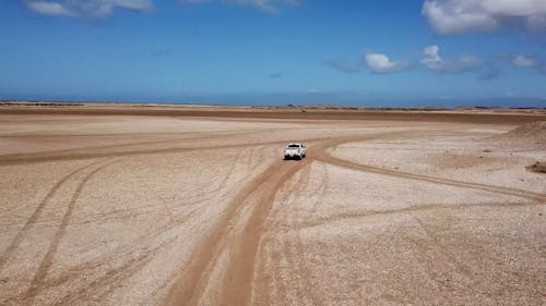 A Pickup Truck Is Travelling On A Desert  Road At Daytime