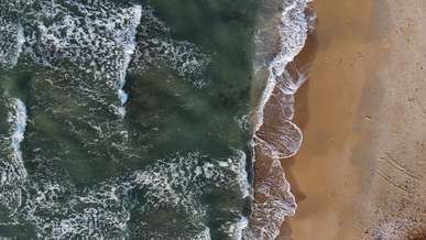 aerial footage of sea waves kissing the shore