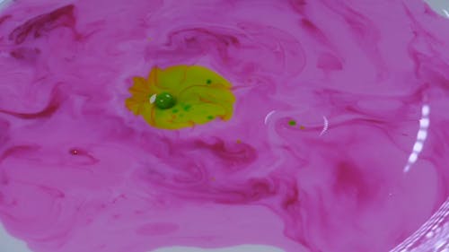 Pouring Yellow Paint On a Pink Paint