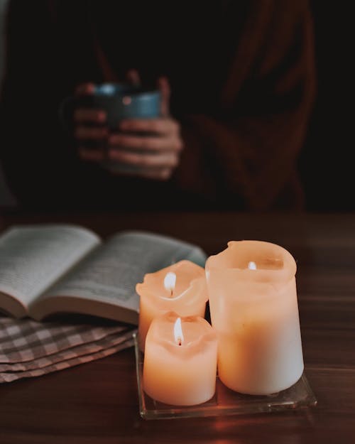 A Person Reading A Book Using Candle Lights