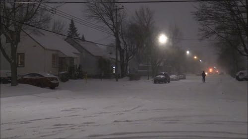 A Man In Black Winter Clothes Walking On A Road Heavily Covered In Snow