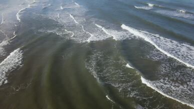 aerial view of ocean waves surfing on coastline