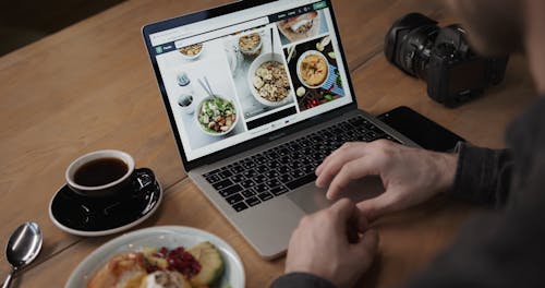 그의 노트북과 디지털 카메라를 통해 음식 사진 촬영 사진을 확인하는 사진 작가