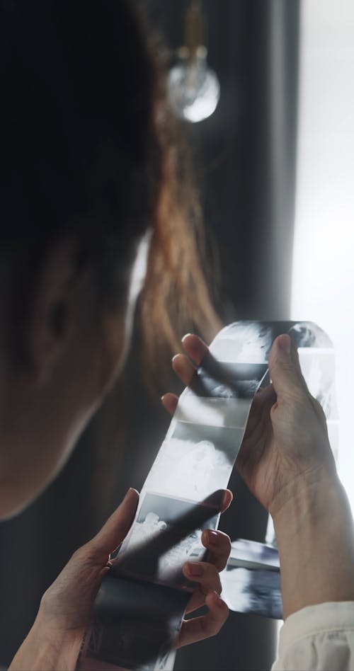 A Photographer Looking At Images Captured In A Camera Film Negatives