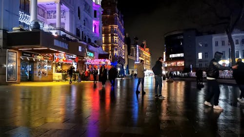 런던 엔터테인먼트 지역에서 젖은 거리를 걷는 사람들