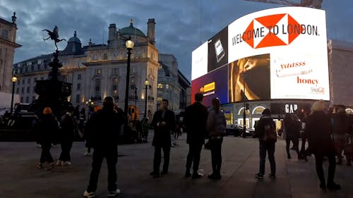 Group Of People Standing In Front Of A Billboard