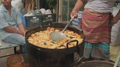 street vendor frying traditional snacks in market