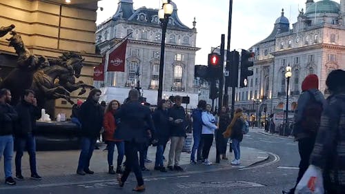 Group Of People Standing On Sidewalk Waiting To Cross The Street