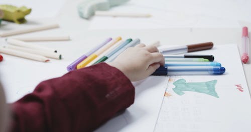 A Young Girl Using Coloring Pen To Draw On A White Paper