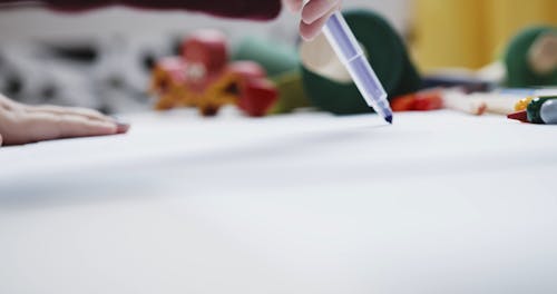 A Kid Drawing A Line Using A Pen