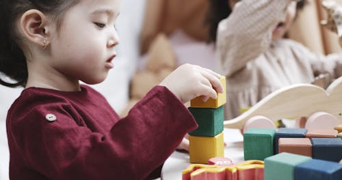 Kids Playing With Wooden Toys Inside A Playroom
