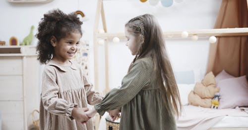 Two Little Girls Holding Hands Playing Round And Round