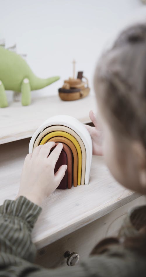 A Girl Is Playing A U-shaped Sorter Wooden Toy 