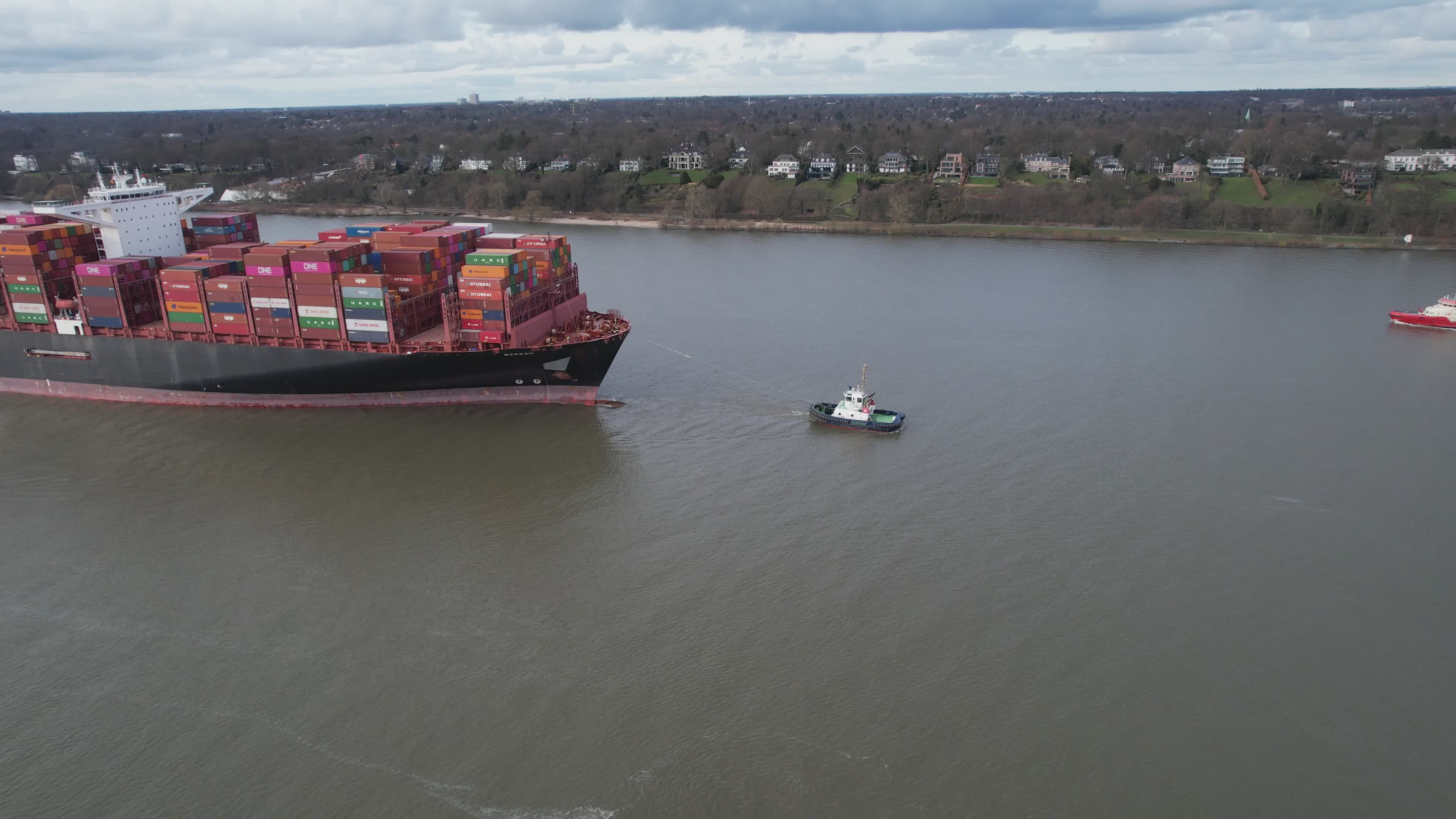 A tugboat guiding a container ship many times its size
