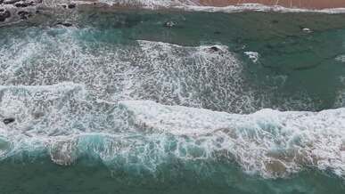 aerial view of ocean waves crashing on shore