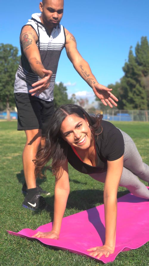 A Man Goofing Beside A Woman Exercising Over A Yoga Mat