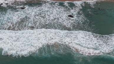 aerial view of ocean waves crashing on shore