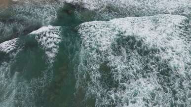 aerial view of ocean waves crashing on shore