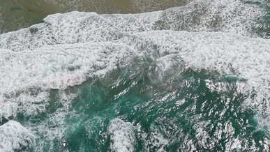 aerial view of ocean waves crashing on shore