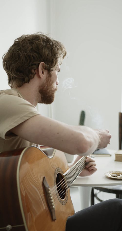 Man Smoking while Playing Guitar