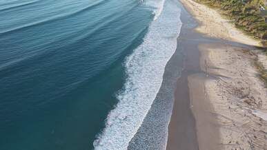 aerial view of pristine ocean waves on sandy beach
