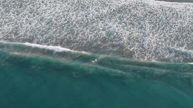 aerial view of surfer riding ocean waves